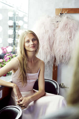 Blondes Model in rosa Kleid im Ankleideraum mit Federjacke und Schminklichtern. — Anna Selezneva Wallpaper