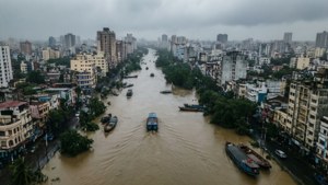 Uma vista aérea de uma cidade inundada durante a monção, barcos nas ruas, estilo documental sombrio.