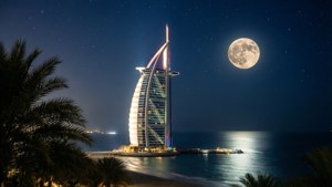 Bulan purnama di atas Burj Al Arab pada tengah malam dengan pantulan.