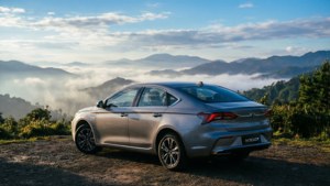 En blå Geely Preface med utsikt över dimmiga berg tidigt på morgonen