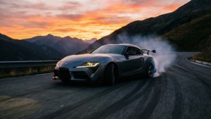Toyota Supra che deriva su una strada di montagna al tramonto, scena cinematografica.
