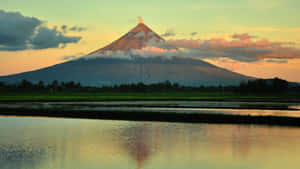 Volcano at sunset with reflection in water and green fields — Snow Mountain Background