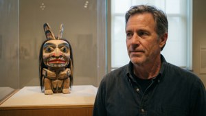 Mann observerer urfolks totemmaske i museummonter