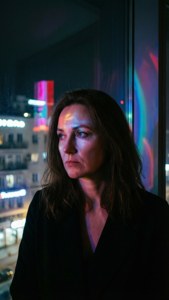 Anna Selezneva avec des lumières néon de la ville se reflétant sur son visage.