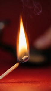 Nahaufnahme eines gerade angezündeten Streichholzes mit kleiner Flamme.