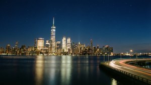 Et rolig nattbilde av Freedom Tower over Hudson, med glitrende refleksjoner og stjernehimmel.