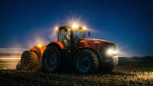 Case IH -traktori työskentelee yöllä tähtien alla etuvalot luoden valojälkiä