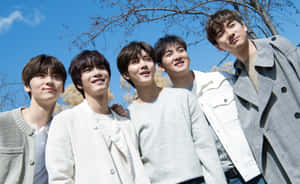 Four smiling young men posing outdoors on a sunny day. — Nuest Picture