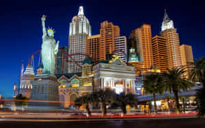Las Vegas skyline at night with Statue of Liberty replica and palm trees.