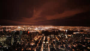 Vista aérea noturna de uma cidade densa com edifícios brilhantes e um céu escuro. — Horizonte de Nova York Papéis de Parede