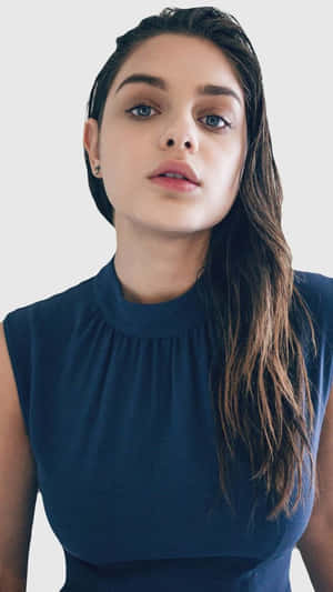 Woman with wet dark hair and blue eyes wearing navy sleeveless top in studio portrait