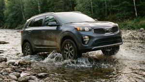 Kia Sorento driving through a river, off-road capability emphasized.