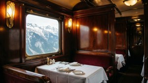 Interior gerbong makan kereta vintage mewah tahun 1920-an dengan detail art deco dan pemandangan gunung bersalju