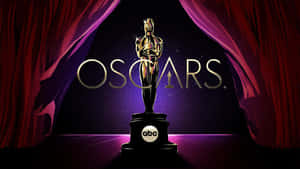 Golden Oscar statue on stage with red curtains and purple lighting. — Oscars Picture