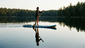 Fridfull paddleboardare på glasklar sjö med perfekt spegling