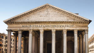 The Pantheon in Rome with its stone columns and inscribed pediment under a clear blue sky. — Baroque Wallpaper