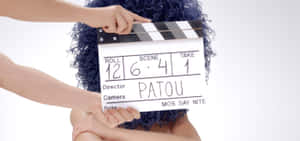 Person with curly hair holding a film clapperboard in a studio. — Luxury Brands Picture