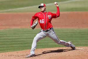 Baseball pitcher in red jersey throwing from mound on sunny field. — Live Wallpaper