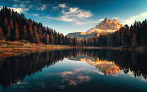 A calm lake reflects a towering mountain and autumn trees under a colorful sky. — Pc Wallpaper