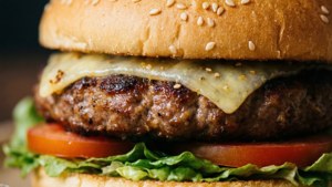 Makro nærbilde av en hamburger med bolle, ost, patty og grønnsaker.