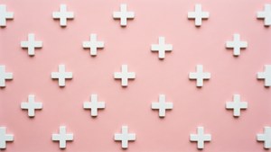 Minimalistisk tapet med vita plustecken på rosa bakgrund.