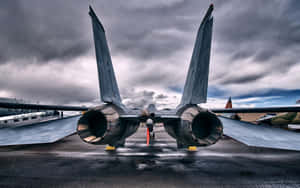 A U.S. Air Force fighter jet on a wet tarmac under a stormy sky.