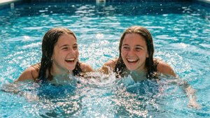 Two cousins enjoying a swim and splashing in a pool.