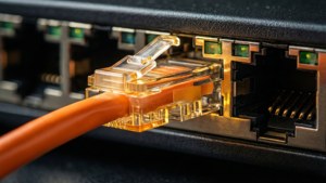 Äärimmäinen lähikuva verkkokytkimen portista, jossa on hehkuva Ethernet-kaapeli.