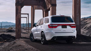 SUV Dodge Durango branco estacionado sob vigas de aço enferrujadas em uma pedreira com montanhas ao fundo. — Esquivar Papéis de Parede
