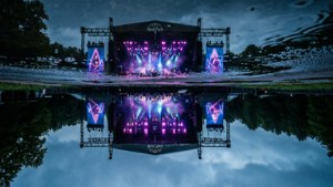 Taiteellinen heijastus Rock im Park -päälavasta sateisessa lammikossa neonvärein