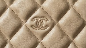 Un fondo abstracto con el icónico patrón acolchado y logotipo de Chanel, lujo sutil.