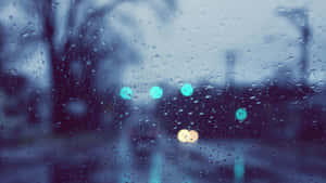 Raindrops on a window with blurred city lights glowing in the background. — Rainy Nature Picture