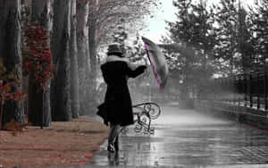 Mulher de casaco preto segurando guarda-chuva na chuva ventosa perto de banco de parque. — Fundo chuvoso Papéis de Parede