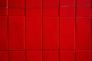 Close-up of red tiled wall with visible grout lines and surface texture. — Plain Red Wallpaper