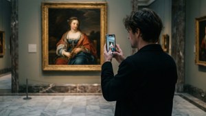 Seseorang di museum melihat pantulan lukisan di layar ponsel mereka, bukan secara langsung.