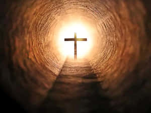A cross silhouette glowing at the end of a dark tunnel with a path leading toward it.
