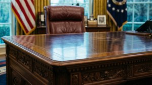 En detaljerad närbild av det ikoniska Resolute Desk med flaggor i bakgrunden