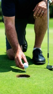 Frank Lickliter II kneler for å plukke opp en golfball fra hullet.