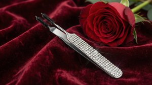 Romantisk bakgrunnsbilde av en rhinestonebelagt pinsett på fløyel med en rose.