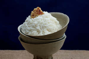Stacked ceramic bowls filled with white rice and topped with a crispy garnish. — Angourie Rice Picture