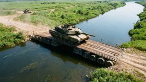 Een realistisch luchtbeeld van een Leopard 2-tank die een rivier oversteekt op een pontonbrug.