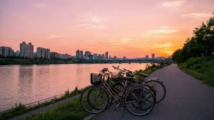 Ein friedlicher Sonnenuntergang entlang des Han-Flusses mit Fahrrädern und der Skyline von Seoul in der Ferne.