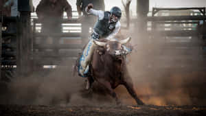 Bull rider in helmet and vest riding bucking bull in dusty rodeo arena.