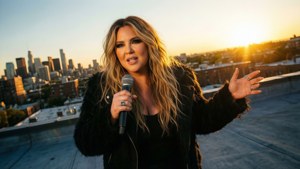 Kelly Clarkson si esibisce su un tetto al tramonto con vista sulla città.