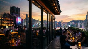 A romantic, cinematic rooftop bar scene overlooking Mong Kok’s skyline as the sun sets.