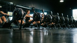 Lav vinkel optagelse af romaskiner i et mørkt fitnesscenter med lysende skærme.