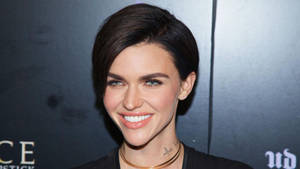 Woman with short dark hair and blue eyes smiling at camera at event. — Ruby Wallpaper