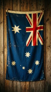 Gammelt og slidt australsk flag hængt på en trævæg, vintage følelse.