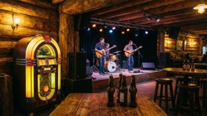 Band playing in old bar with jukebox and wooden decor.