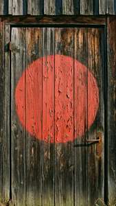 A red circle on a weathered wooden barn door with peeling paint.